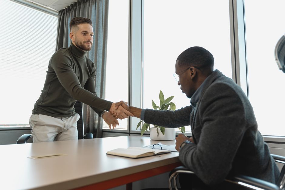 Two businessmen shaking hands in a modern office after a successful meeting.