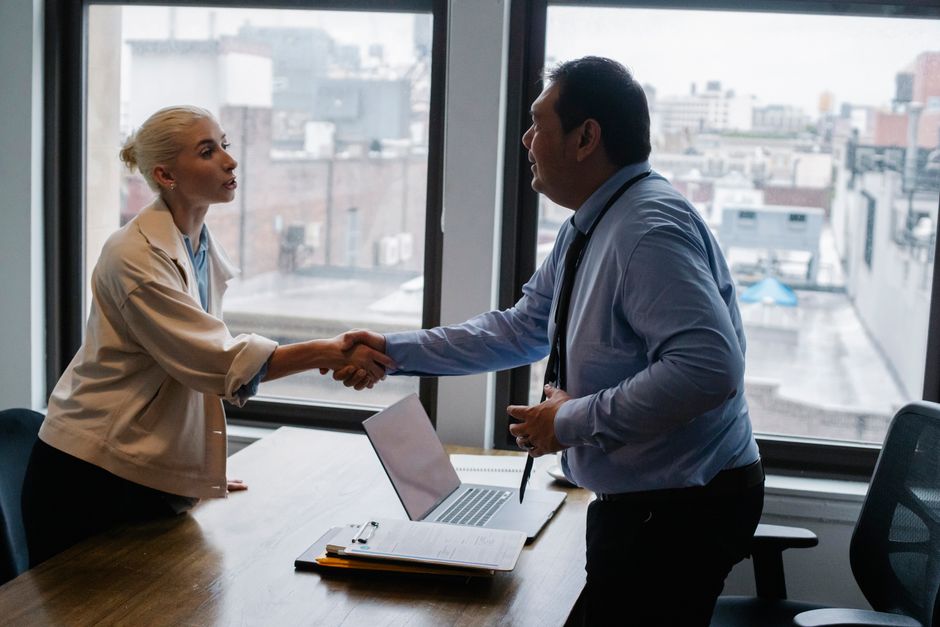 Young female candidate shaking hands with employer before job interview.