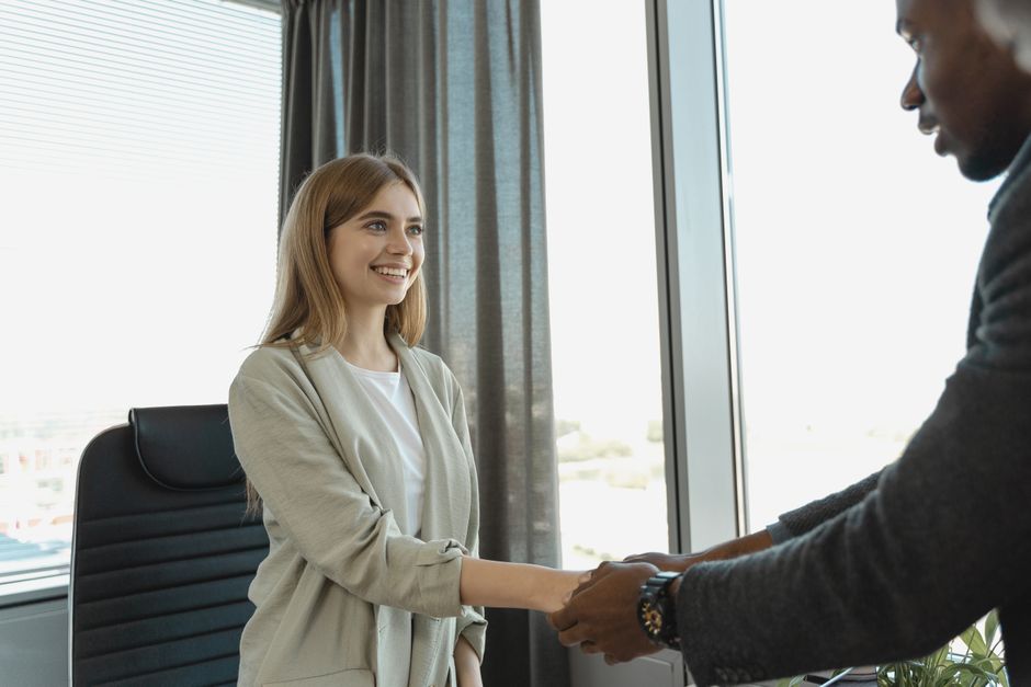 Woman smiling and shaking hands at a business office.